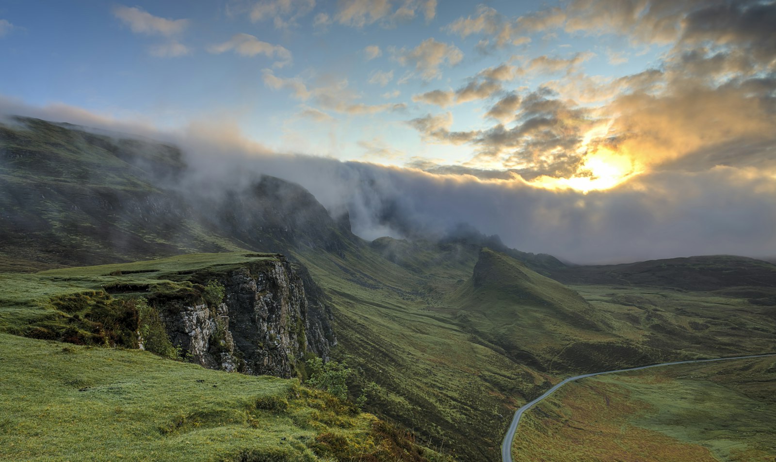 Mist rolling across green mountain ridges as the sun breaks through the clouds